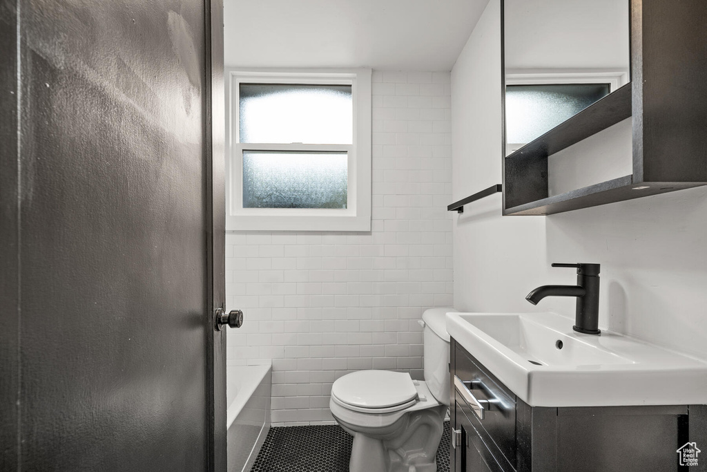 Bathroom featuring tile floors, tile walls, vanity, and toilet