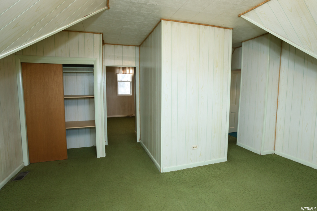 Additional living space with dark carpet and wood walls