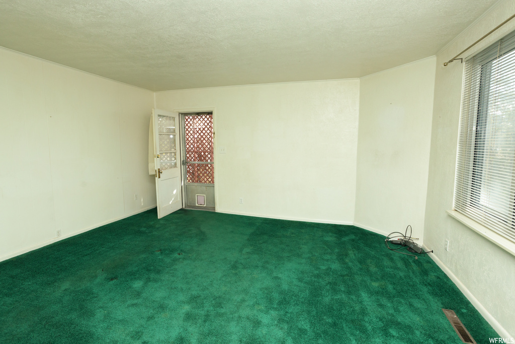 Unfurnished room featuring dark colored carpet and a textured ceiling