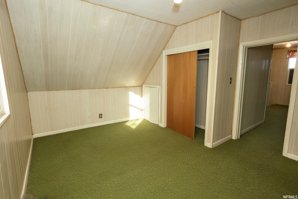 Bonus room featuring lofted ceiling and dark colored carpet