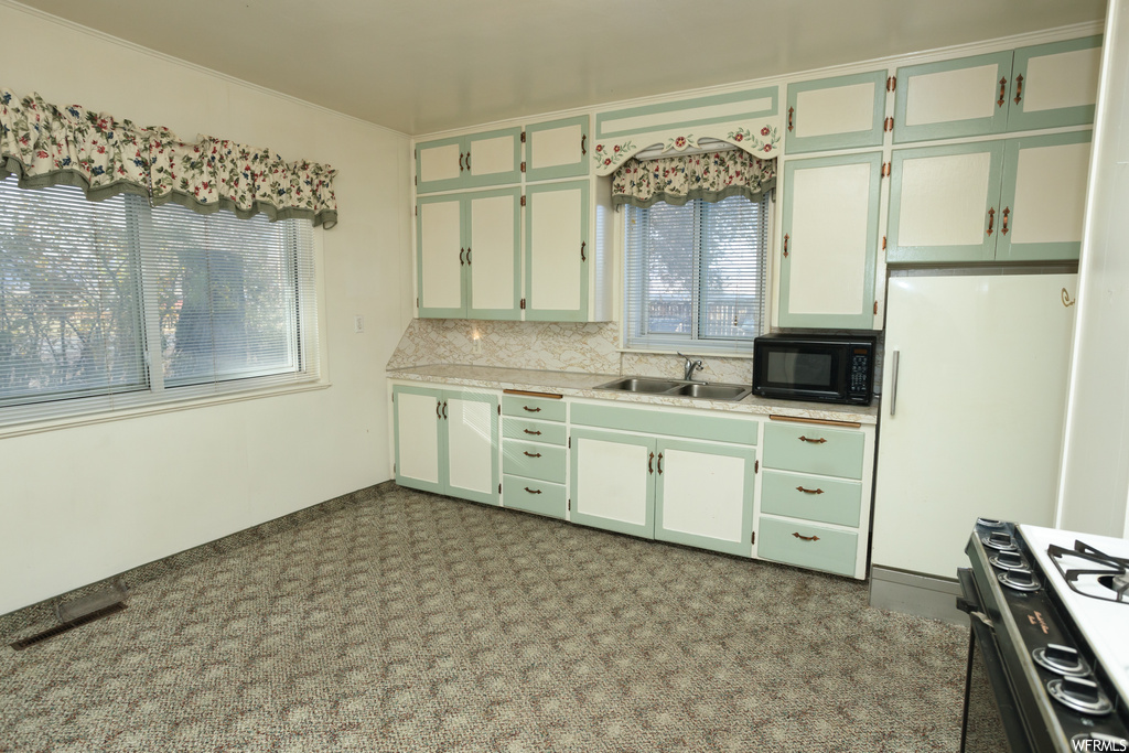 Kitchen featuring range, backsplash, sink, and light carpet