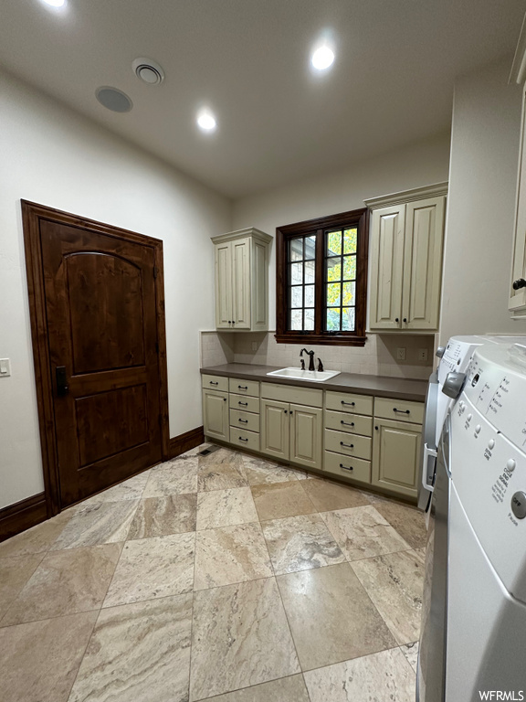 Kitchen with light tile floors, sink, separate washer and dryer, and backsplash