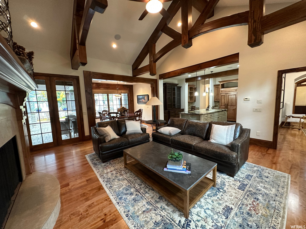 Living room with dark wood-type flooring, high vaulted ceiling, a premium fireplace, ceiling fan, and beam ceiling