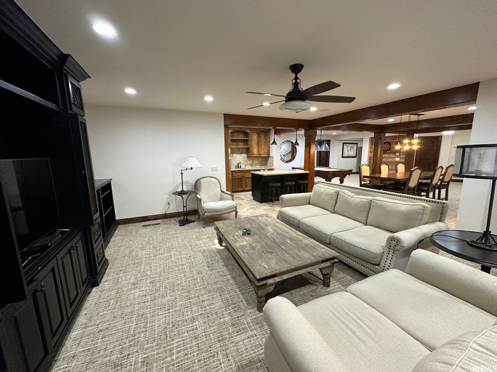 Carpeted living room with ceiling fan and beam ceiling