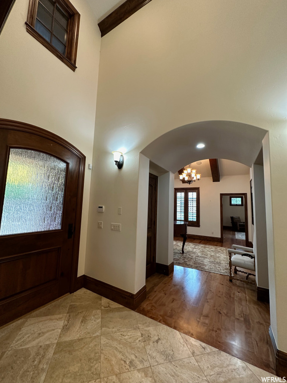 Entryway with lofted ceiling with beams, a notable chandelier, and light tile floors