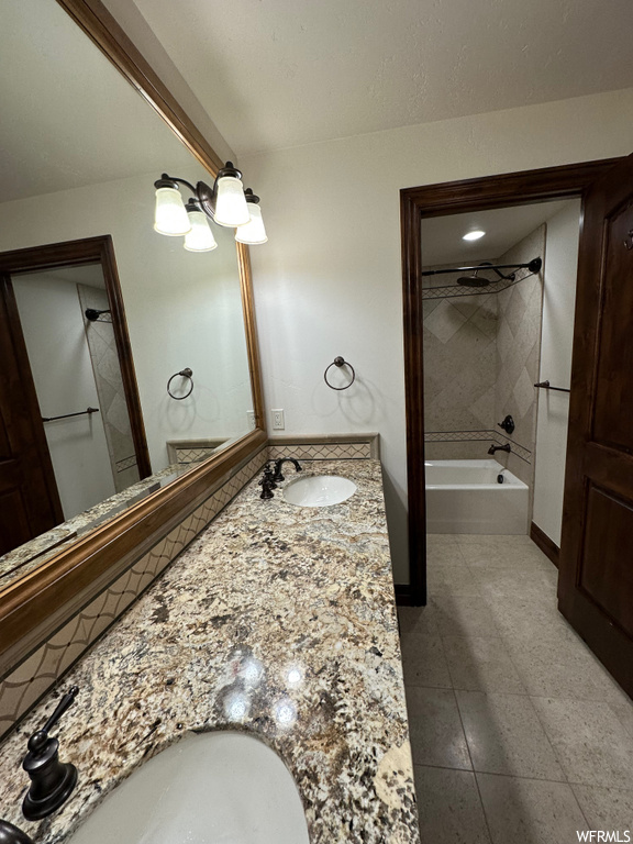 Bathroom with tiled shower / bath, dual vanity, and tile flooring
