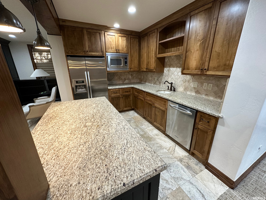 Kitchen with sink, stainless steel appliances, decorative light fixtures, backsplash, and light tile floors