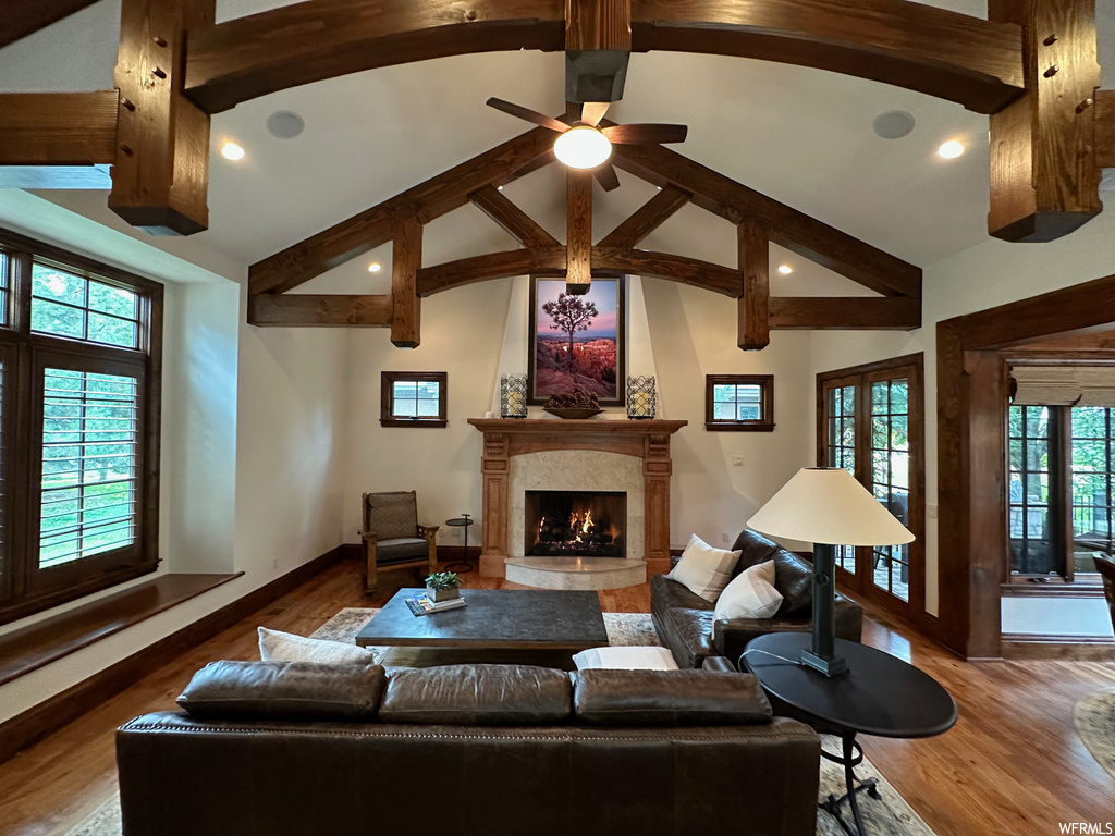 Living room featuring a premium fireplace, vaulted ceiling with beams, ceiling fan, and dark hardwood / wood-style flooring