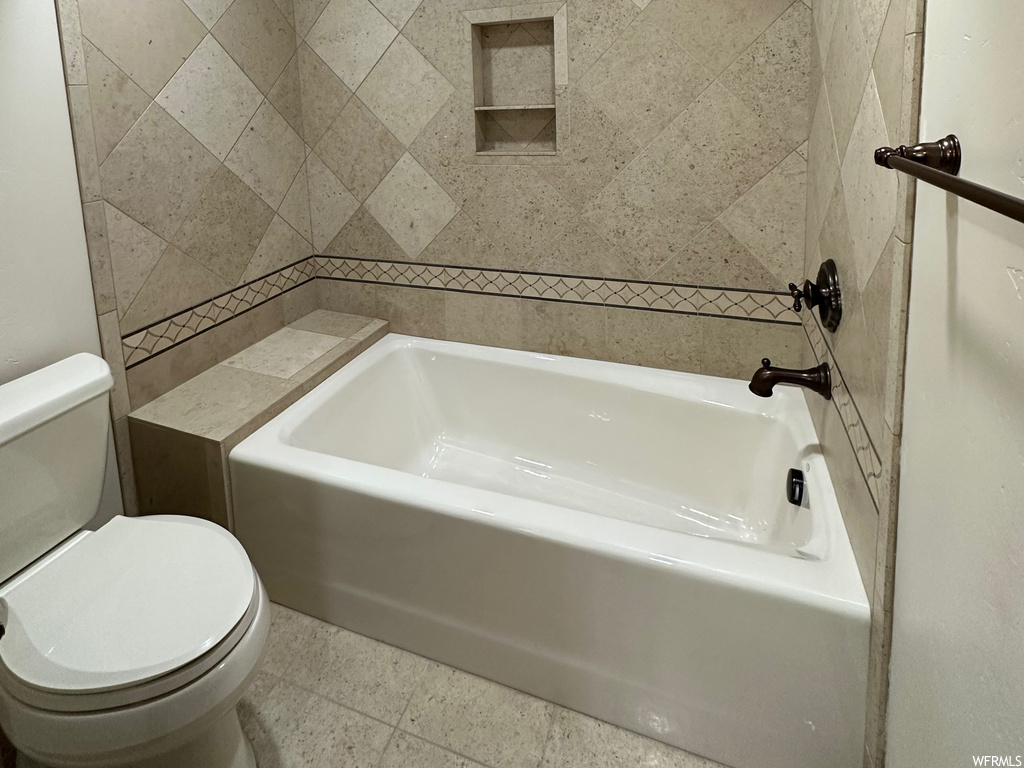 Bathroom featuring toilet, tile floors, and tiled shower / bath