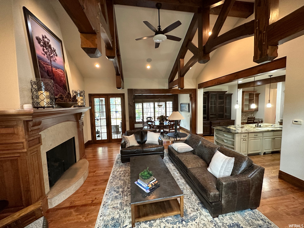 Living room with high vaulted ceiling, a premium fireplace, ceiling fan, wood-type flooring, and beam ceiling