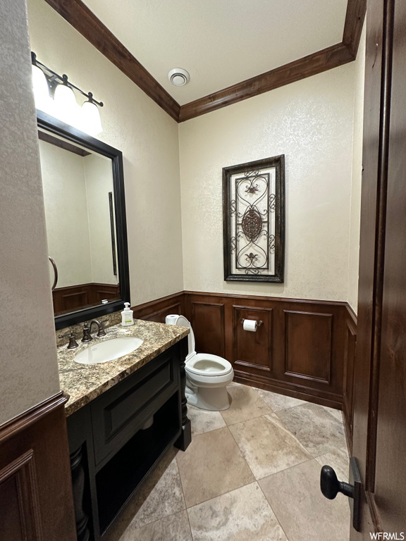 Bathroom with toilet, ornamental molding, vanity with extensive cabinet space, and tile flooring