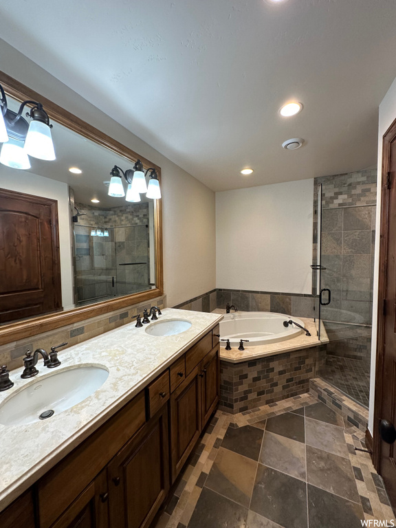 Bathroom with dual sinks, shower with separate bathtub, tile floors, and vanity with extensive cabinet space