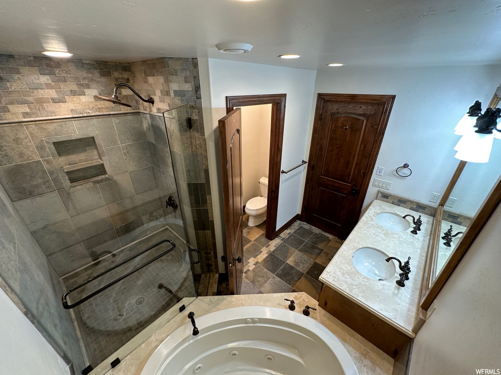 Bathroom featuring toilet, tile floors, a shower with door, and dual bowl vanity