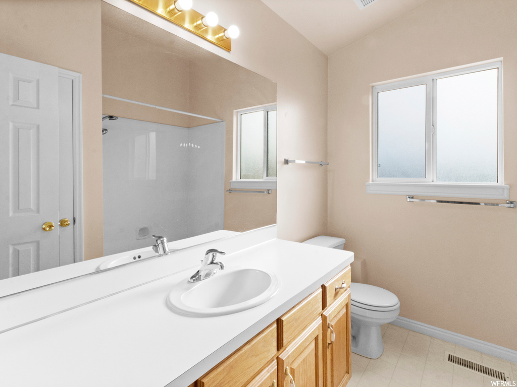 Bathroom featuring lofted ceiling, toilet, tile floors, and plenty of natural light