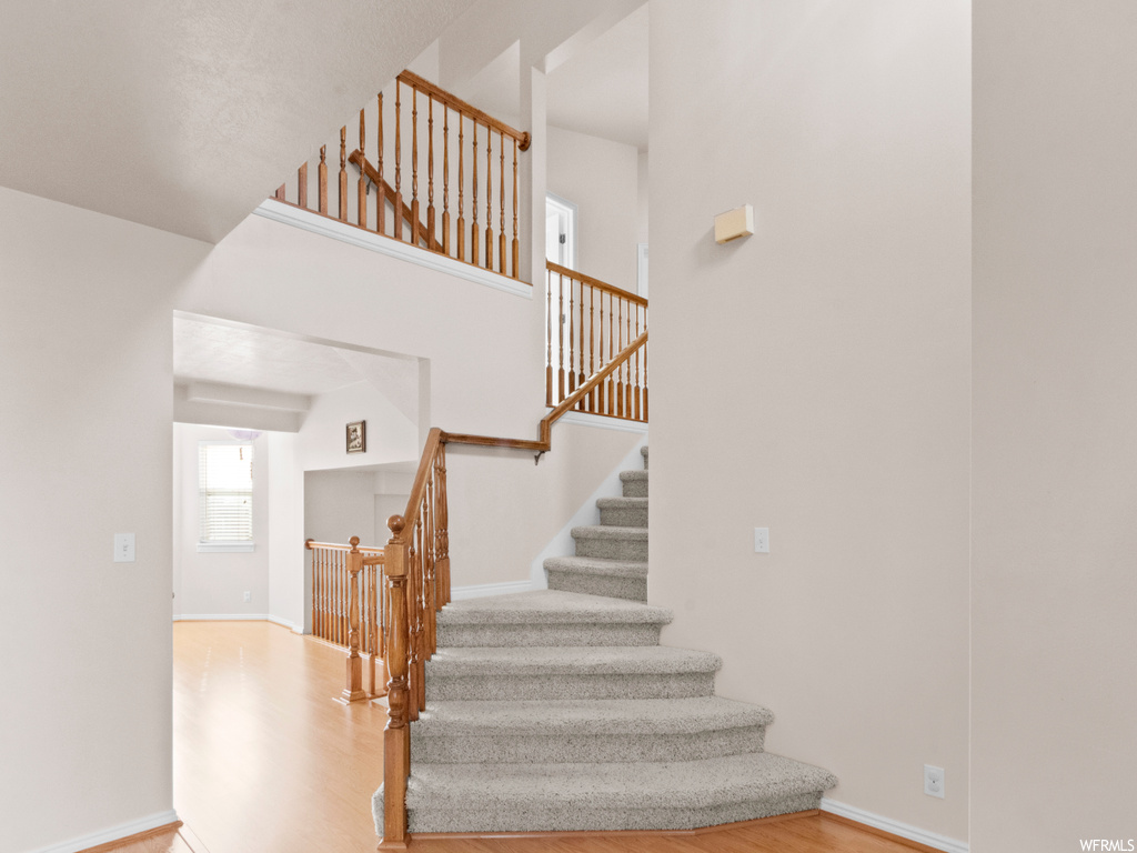 Staircase with light hardwood / wood-style flooring and a high ceiling