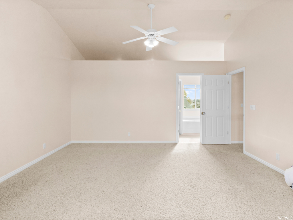 Spare room featuring light colored carpet, ceiling fan, and high vaulted ceiling