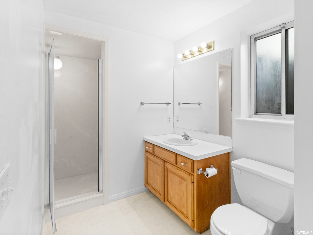 Bathroom featuring toilet, tile floors, walk in shower, and vanity with extensive cabinet space