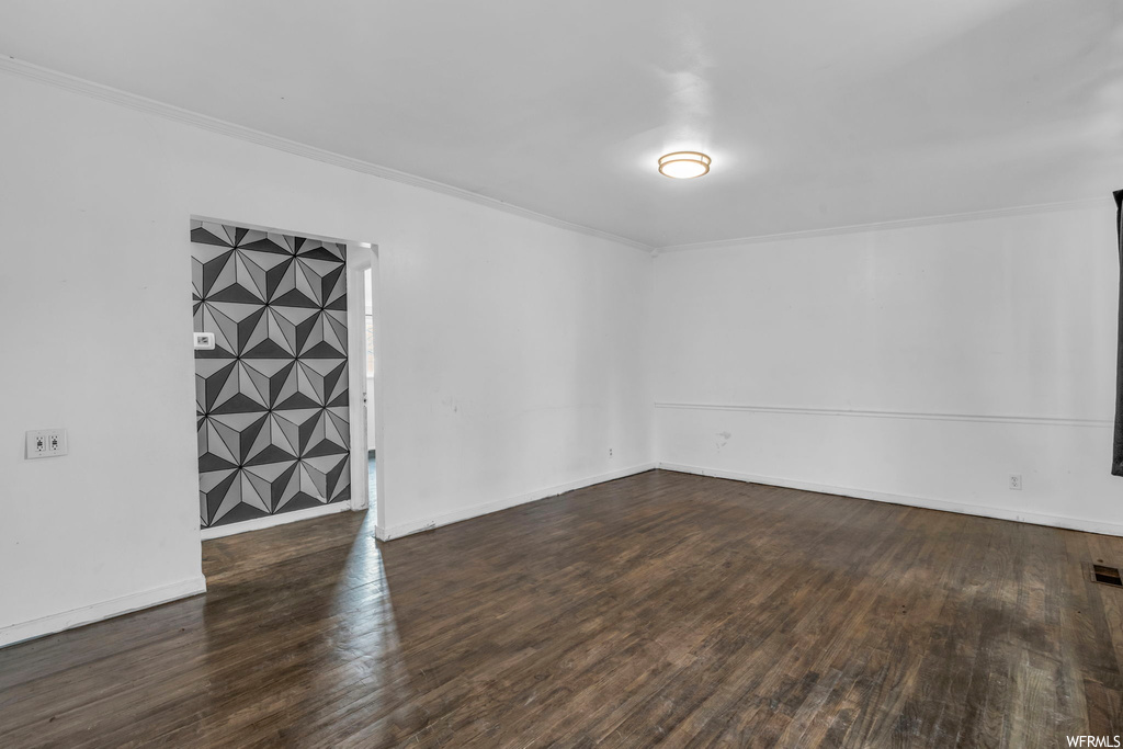 Unfurnished room featuring ornamental molding and dark hardwood / wood-style flooring