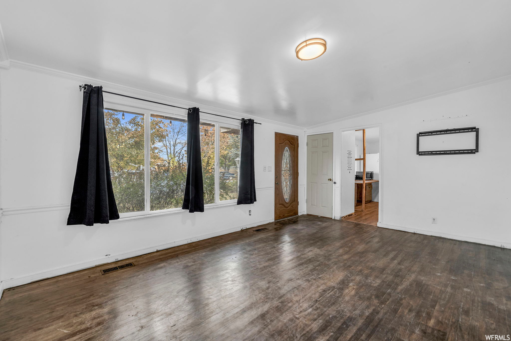 Unfurnished room featuring dark wood-type flooring and ornamental molding