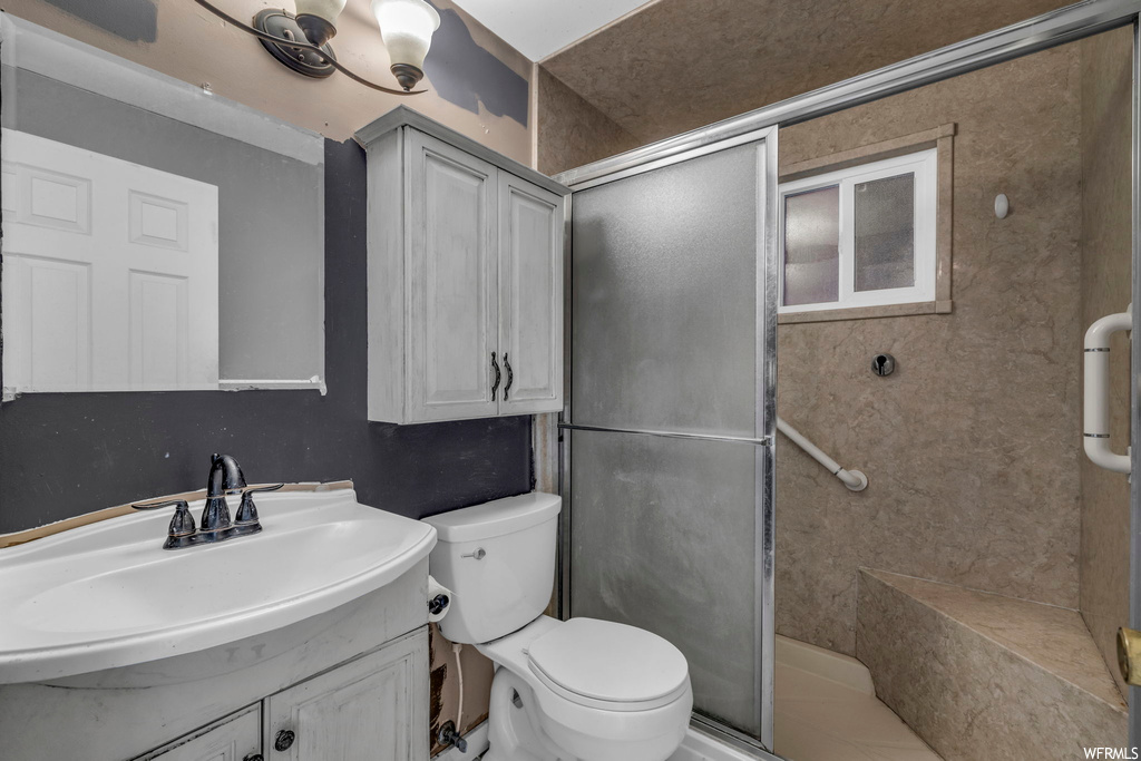Bathroom with toilet, large vanity, and a shower with shower door