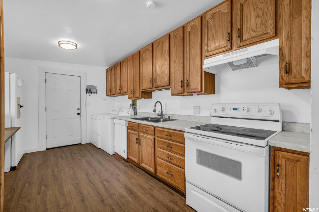 Kitchen featuring white appliances, independent washer and dryer, dark hardwood / wood-style flooring, and sink