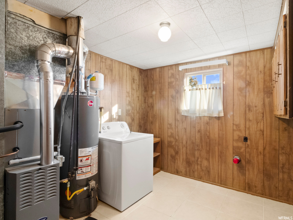 Laundry area with washer / dryer, wooden walls, water heater, and light tile flooring