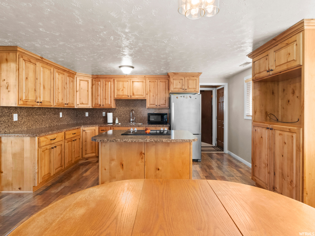 Kitchen featuring a center island, black appliances, tasteful backsplash, and hardwood / wood-style floors