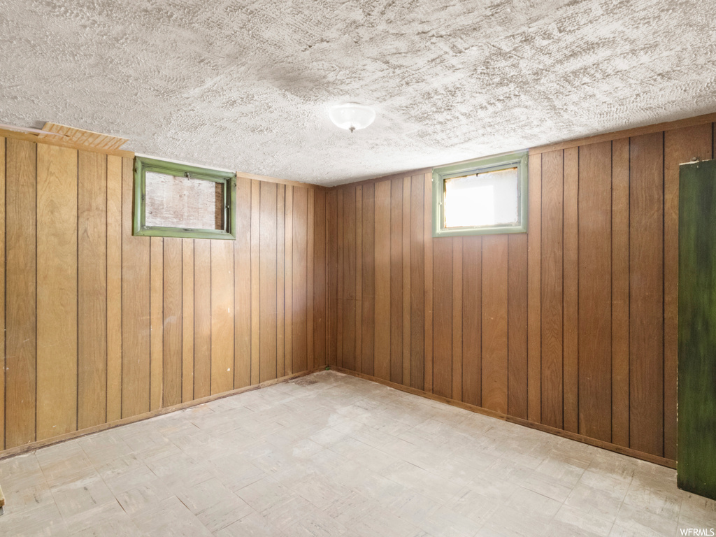 Basement featuring a textured ceiling and wooden walls