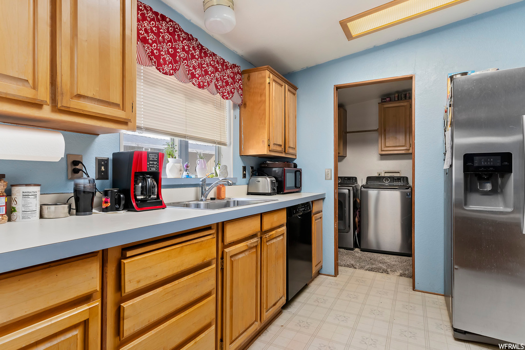 Kitchen with sink, light tile flooring, stainless steel appliances, washing machine and dryer, and lofted ceiling