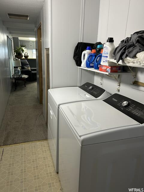 Washroom featuring washing machine and dryer and light carpet