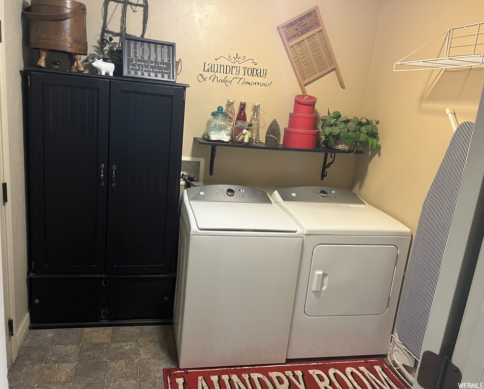 Laundry room with hookup for a washing machine, dark tile floors, cabinets, and washing machine and dryer