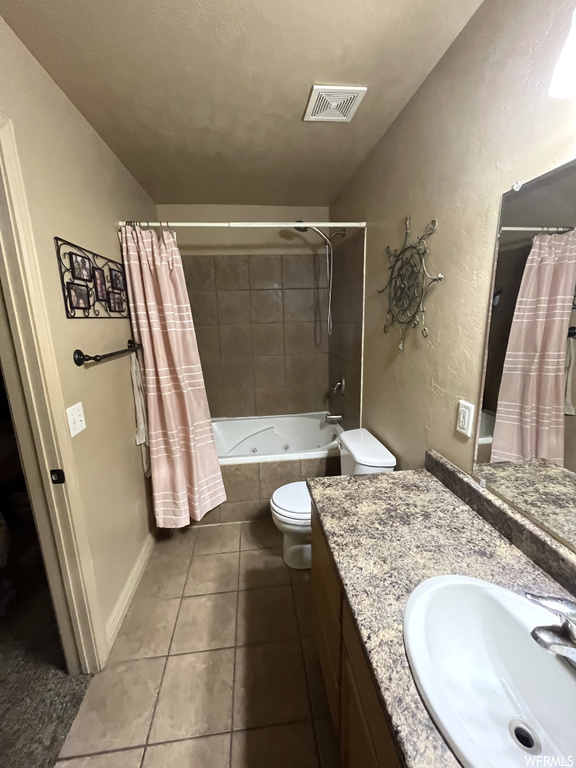 Full bathroom featuring oversized vanity, toilet, tile floors, and shower / tub combo