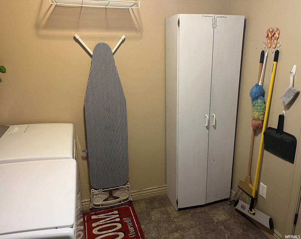 Washroom with dark tile flooring and washer and clothes dryer