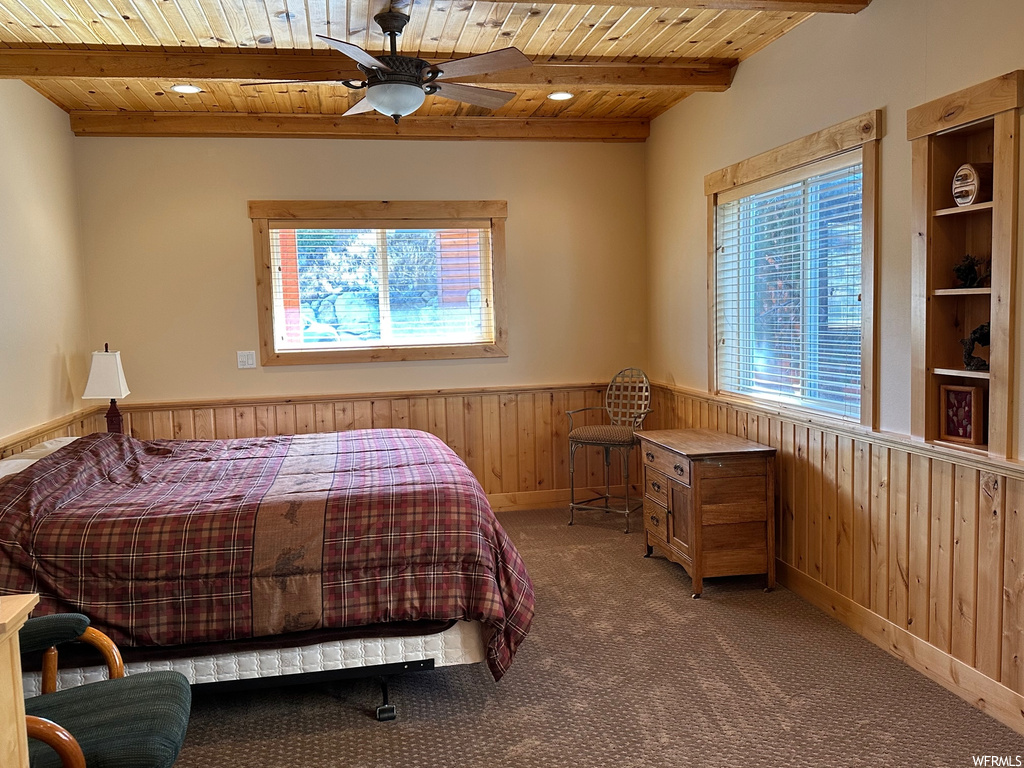 Bedroom featuring wood ceiling, ceiling fan, beam ceiling, and dark colored carpet
