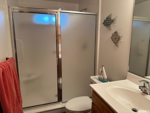 Bathroom with toilet, a shower with shower door, and vanity with extensive cabinet space