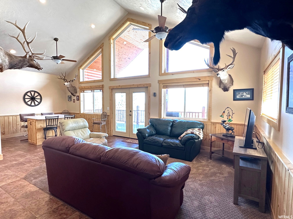Living room with french doors, ceiling fan, light tile flooring, and high vaulted ceiling