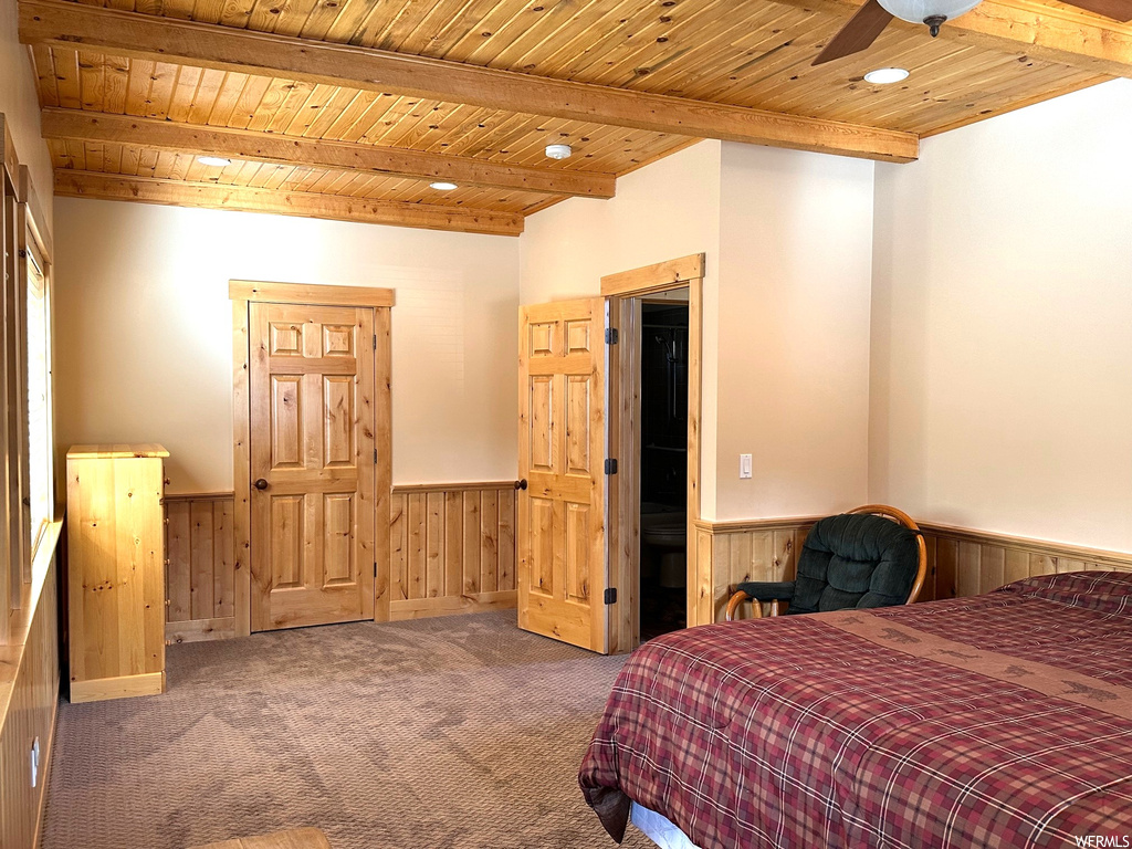 Carpeted bedroom featuring beam ceiling, ceiling fan, and wood ceiling