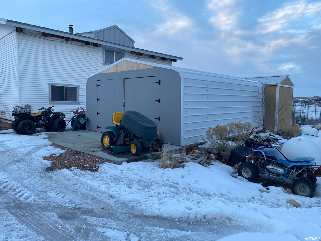 View of snow covered exterior featuring a storage shed