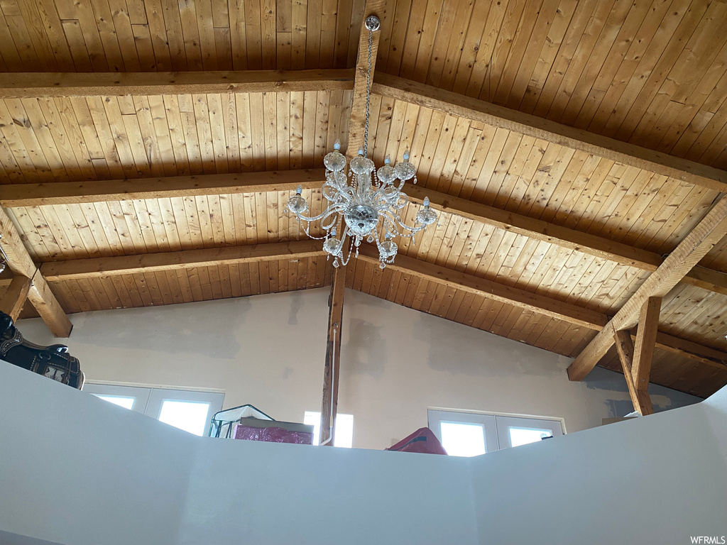 Details with an inviting chandelier, beamed ceiling, and wooden ceiling