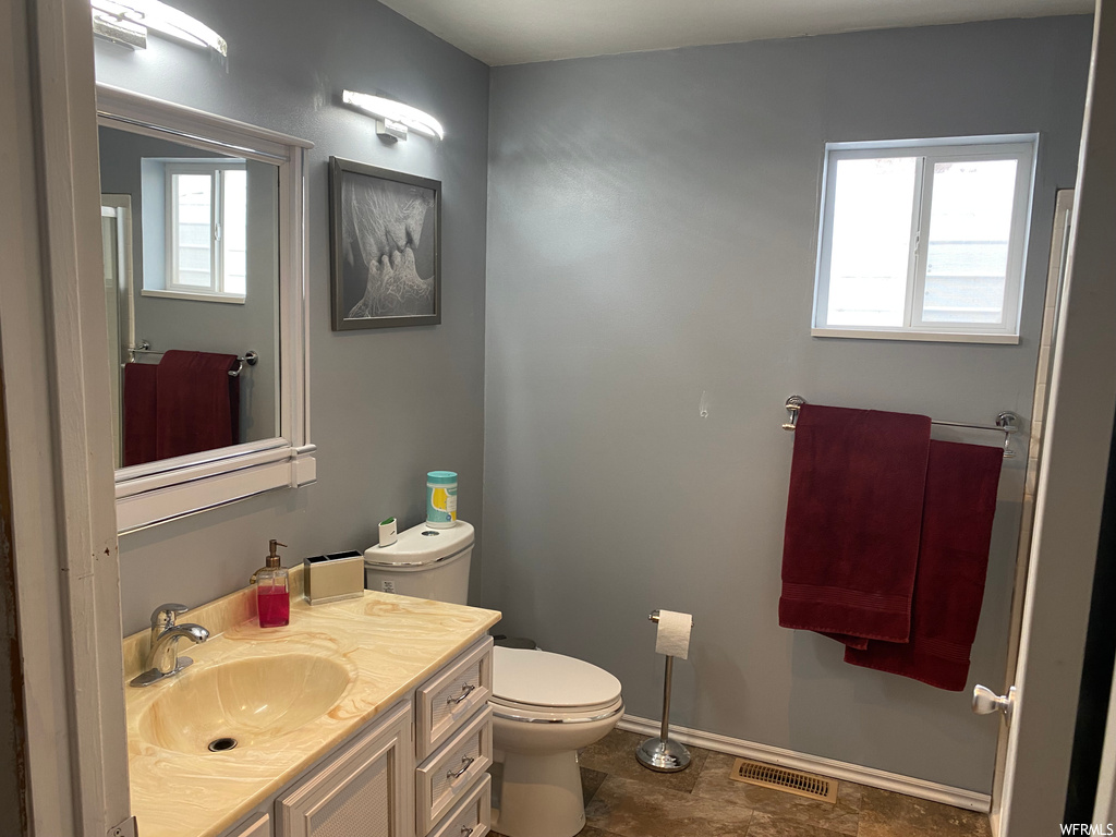 Bathroom with toilet, tile floors, and large vanity