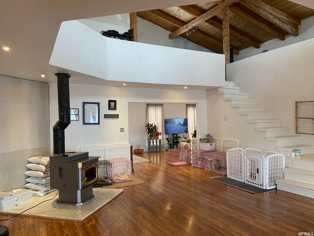 Living room with beamed ceiling, high vaulted ceiling, dark hardwood / wood-style flooring, a wood stove, and wooden ceiling