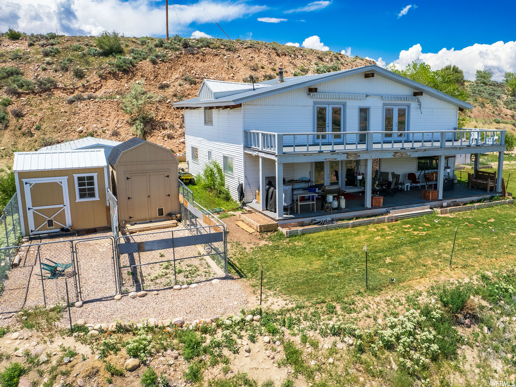 Back of property with a patio area, a storage shed, a deck, and a yard