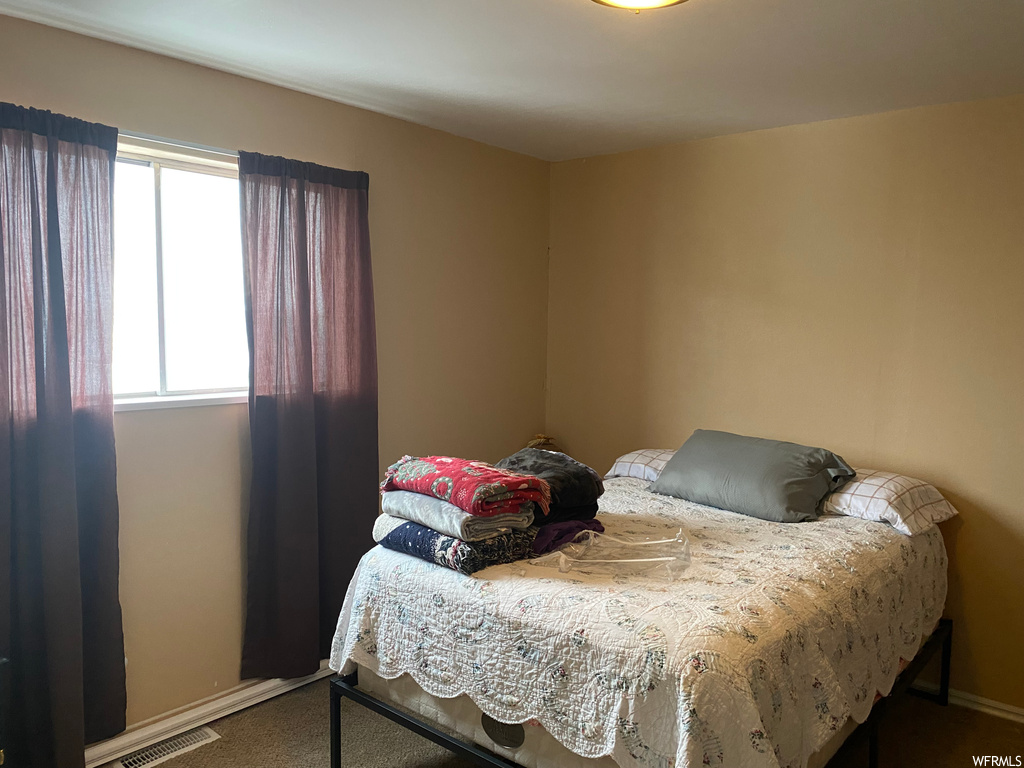 Bedroom featuring multiple windows and carpet flooring