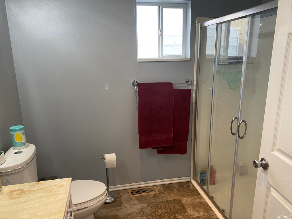 Bathroom featuring toilet, tile floors, and an enclosed shower