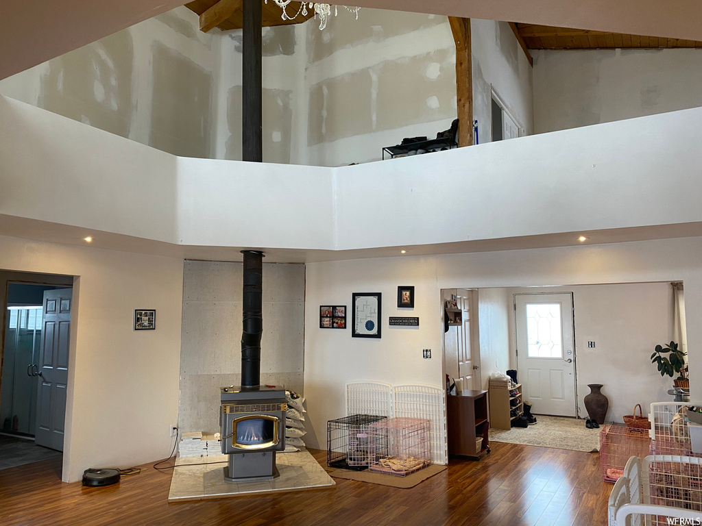 Living room featuring a wood stove, high vaulted ceiling, and wood-type flooring