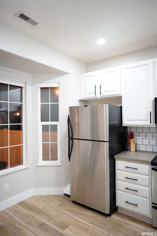 Kitchen featuring white cabinets, light hardwood / wood-style flooring, and stainless steel appliances