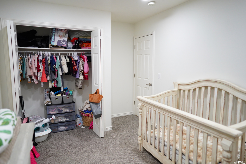 Bedroom with light carpet, a closet, and a crib