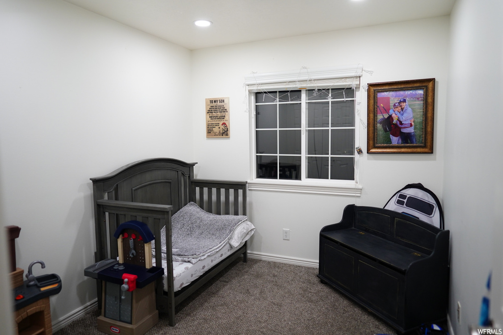 Bedroom featuring dark carpet and a crib