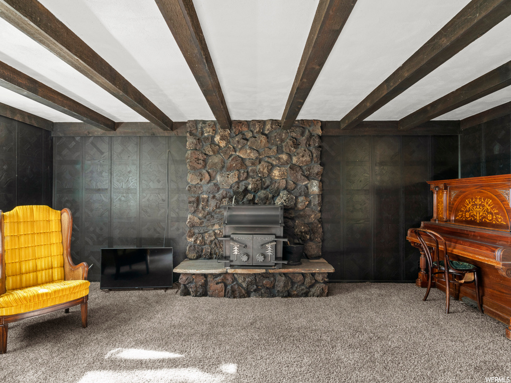 Carpeted living room with a wood stove and beam ceiling