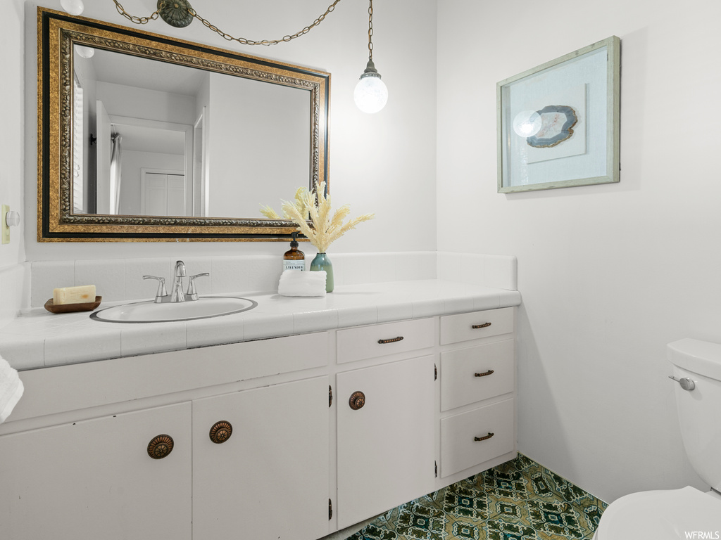 Bathroom featuring toilet, tile flooring, and vanity with extensive cabinet space